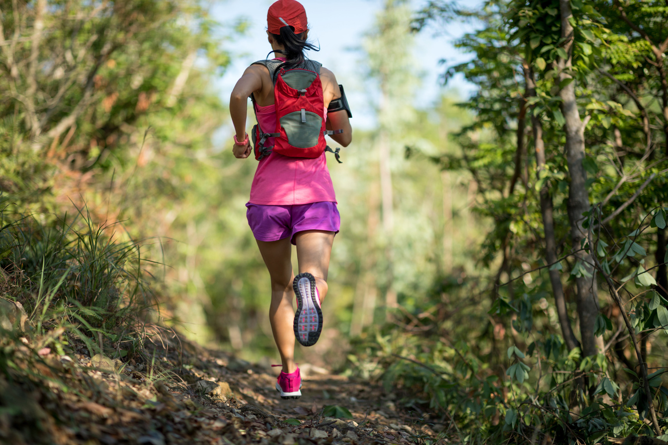 Woman trail runner running in forest trail